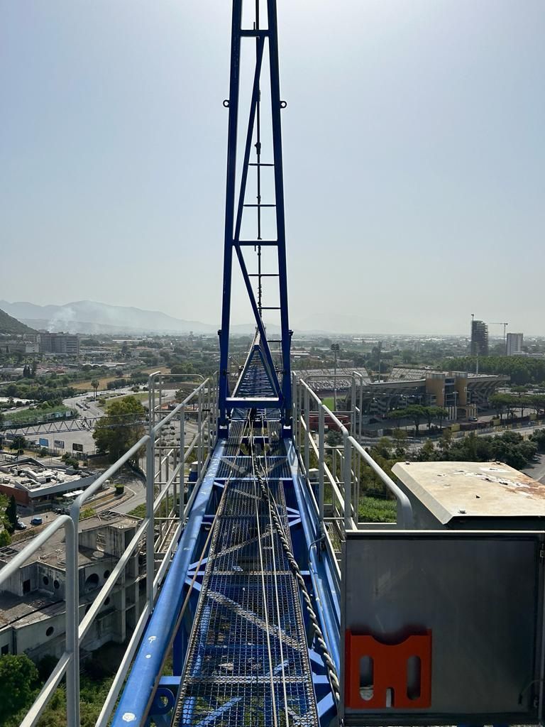 Torre blu di un parco divertimenti con vista sullo skyline della città e sulle montagne sotto un cielo velato