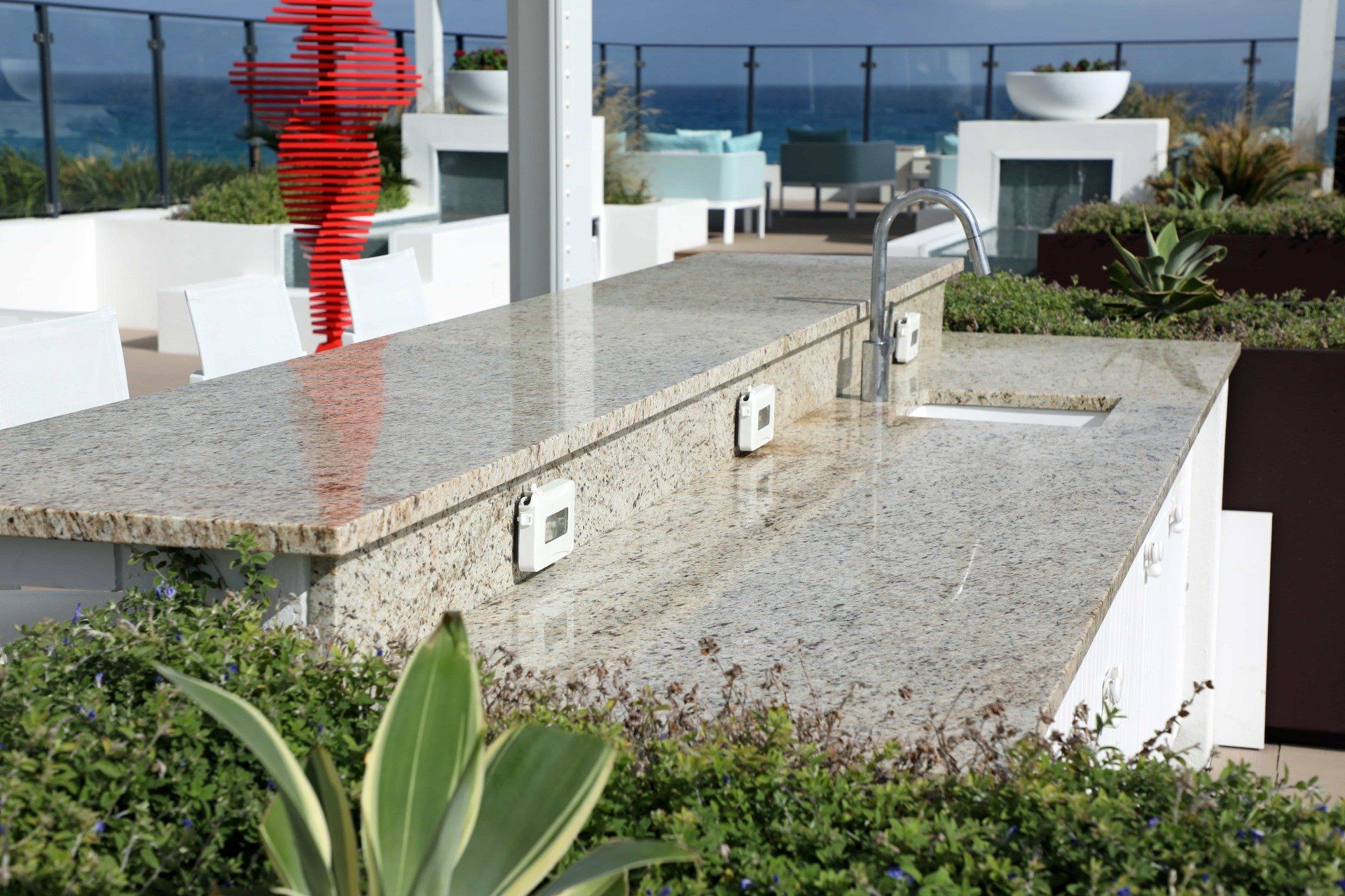 Modern rooftop terrace with stone steps, red sculpture, and ocean view