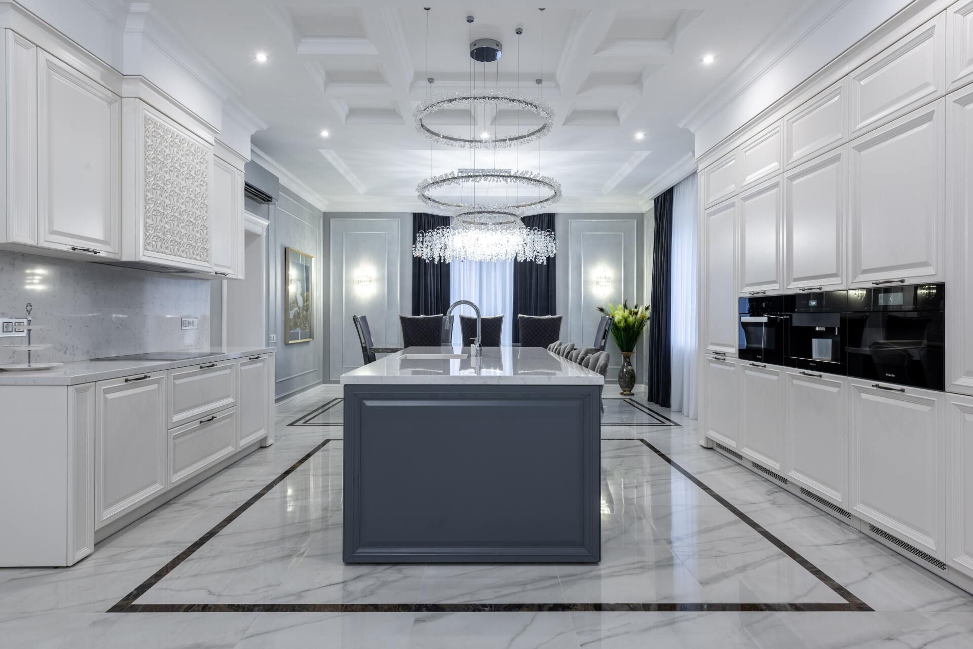 Bright white modern kitchen with marble floors, central island, and built-in appliances
