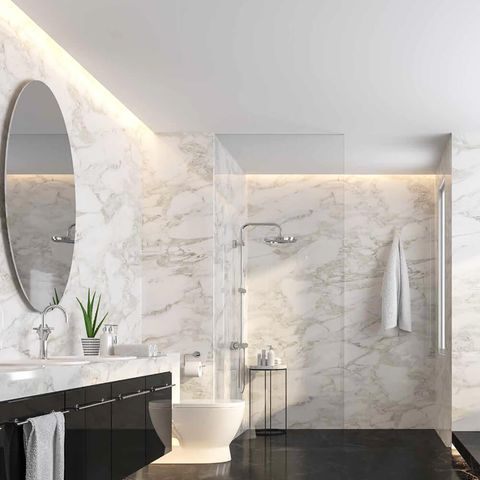 Modern marble bathroom with oval mirror, black vanity, and walk-in shower under soft lighting