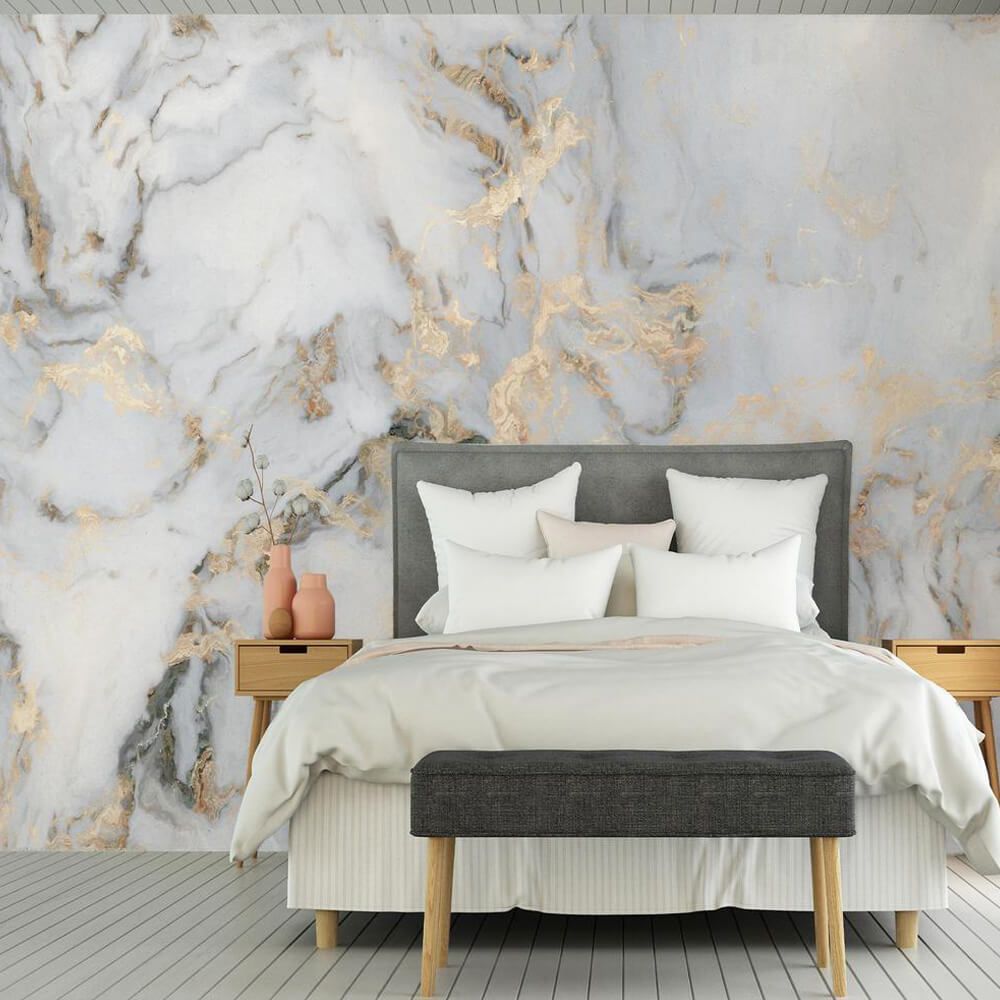 Modern bedroom with a gray upholstered bed, white bedding, wooden nightstands, and a marble-patterned wall mural