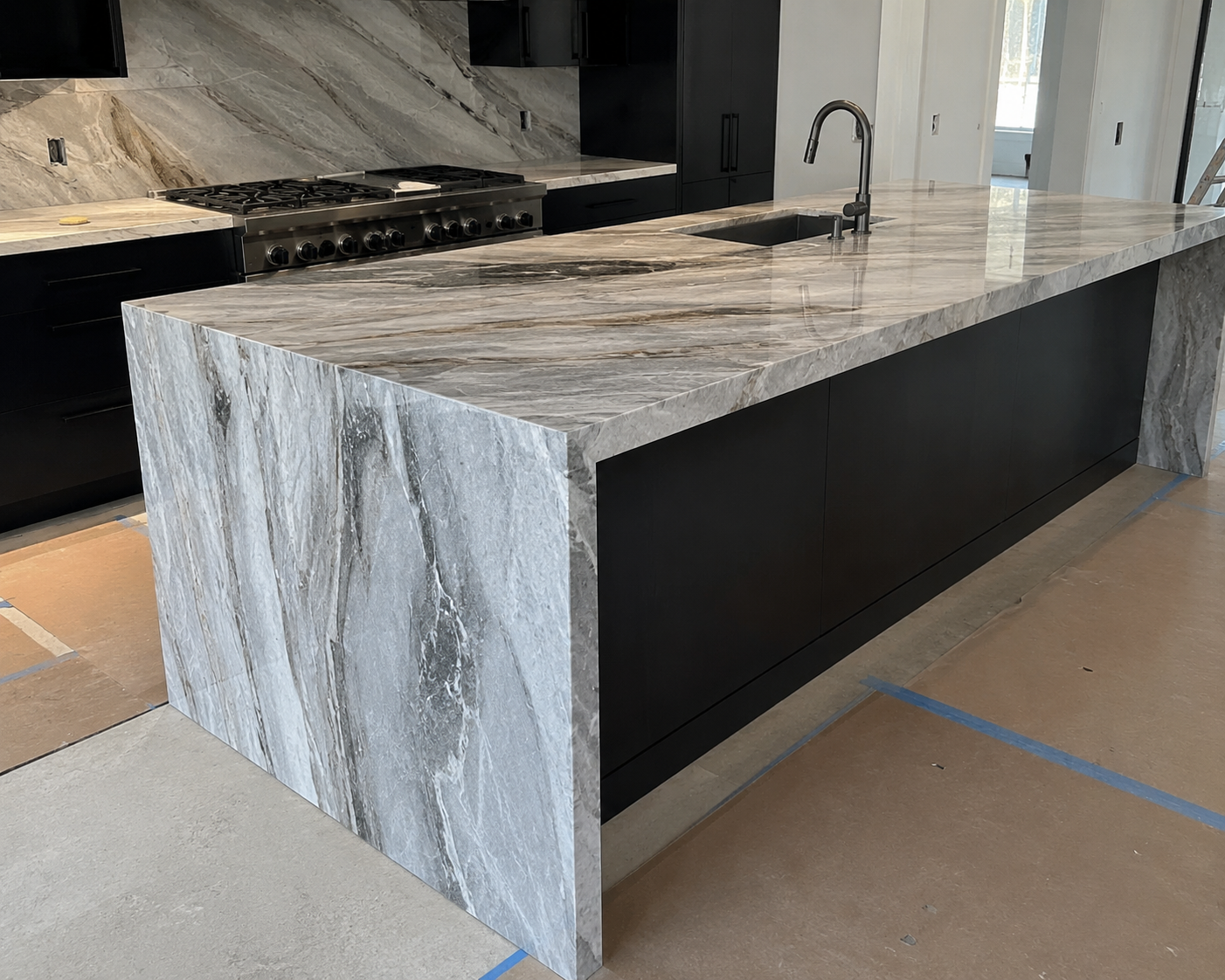 Modern kitchen island with gray stone countertop and black side panel in a showroom
