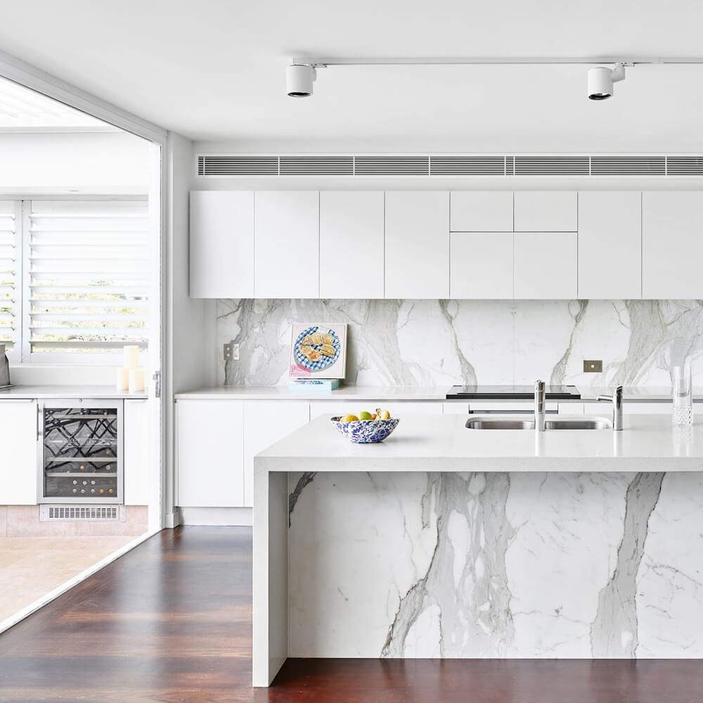 Bright modern kitchen with white cabinets, marble island, and hardwood floors