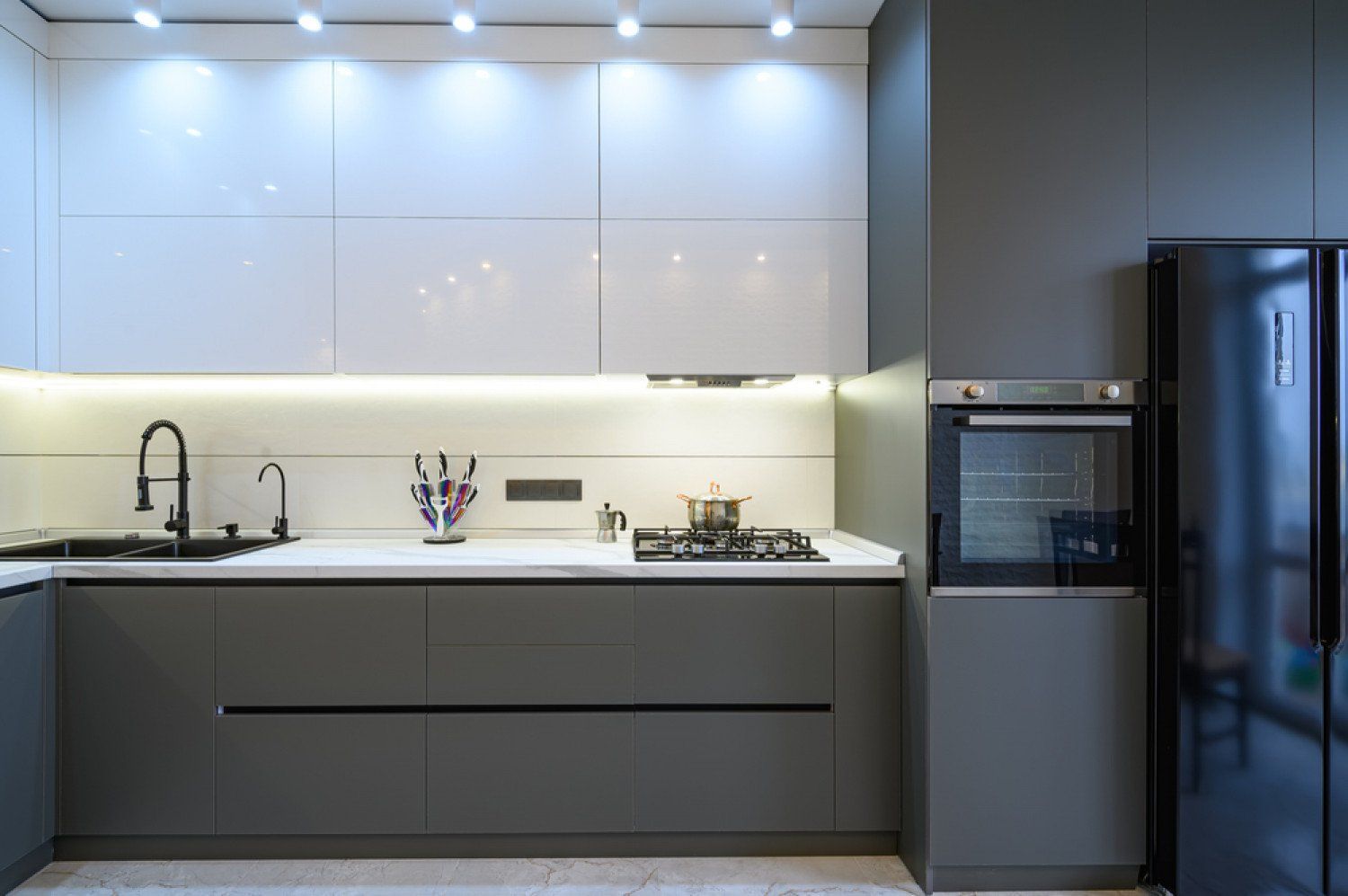 Modern minimalist kitchen with white cabinets, gray island, sink, stove, and stainless steel refrigerator