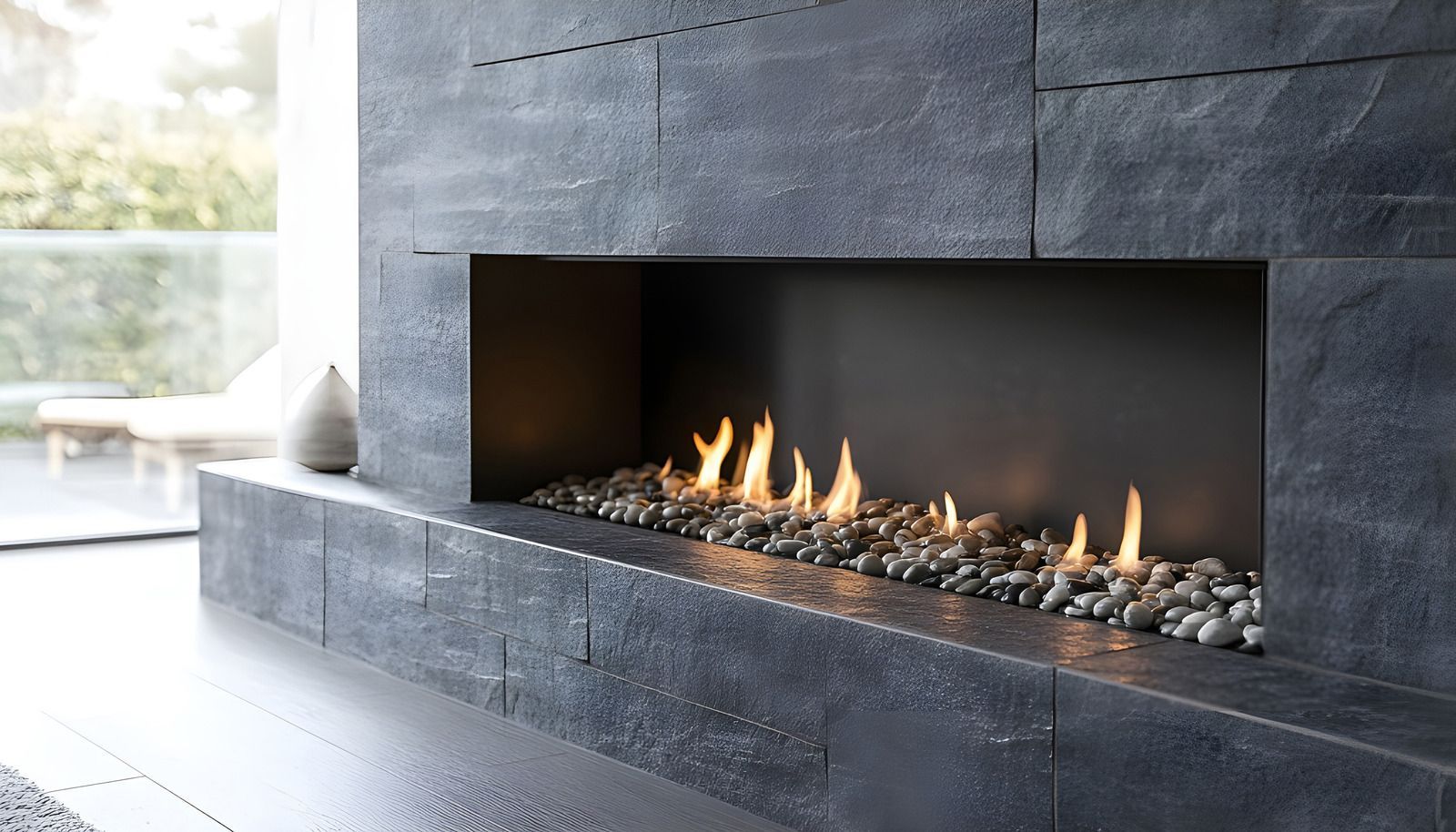Modern dark stone fireplace with a long rectangular fire burning indoors