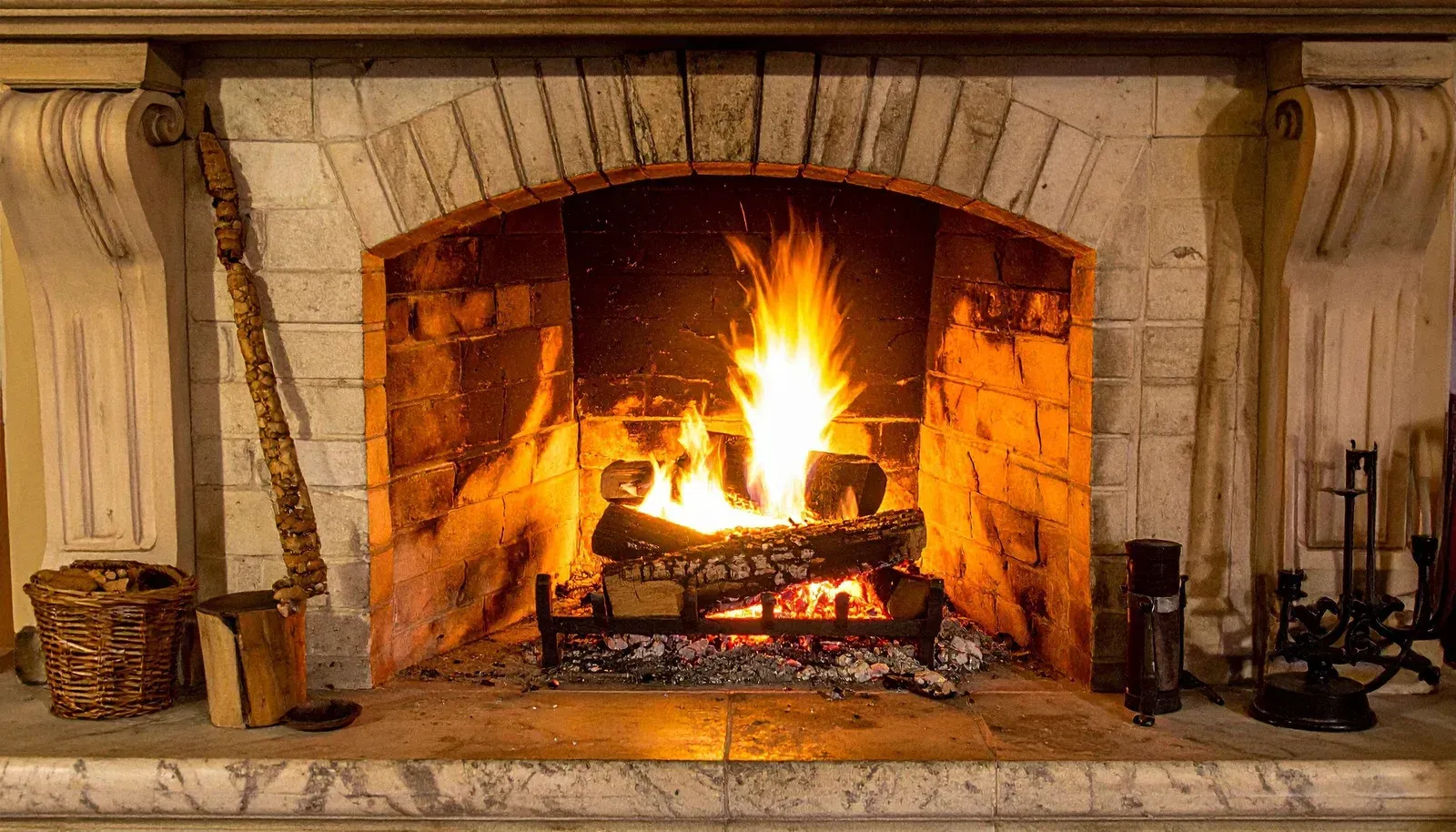 Stone fireplace with a burning fire and logs in a cozy room