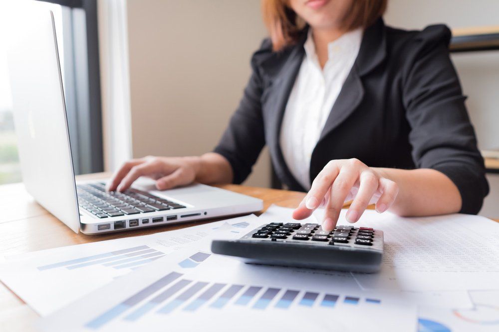 Female Accountant using Calculator & Laptop — BAS Agents in Bundaberg QLD