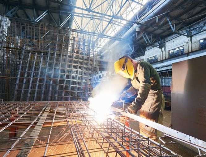 A Man Is Welding A Piece Of Metal In A Factory — Agriweld Engineering in Dubbo, NSW