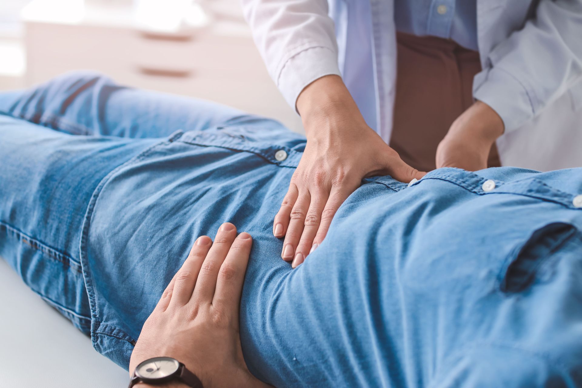 Um médico está examinando o estômago de um paciente com as mãos.