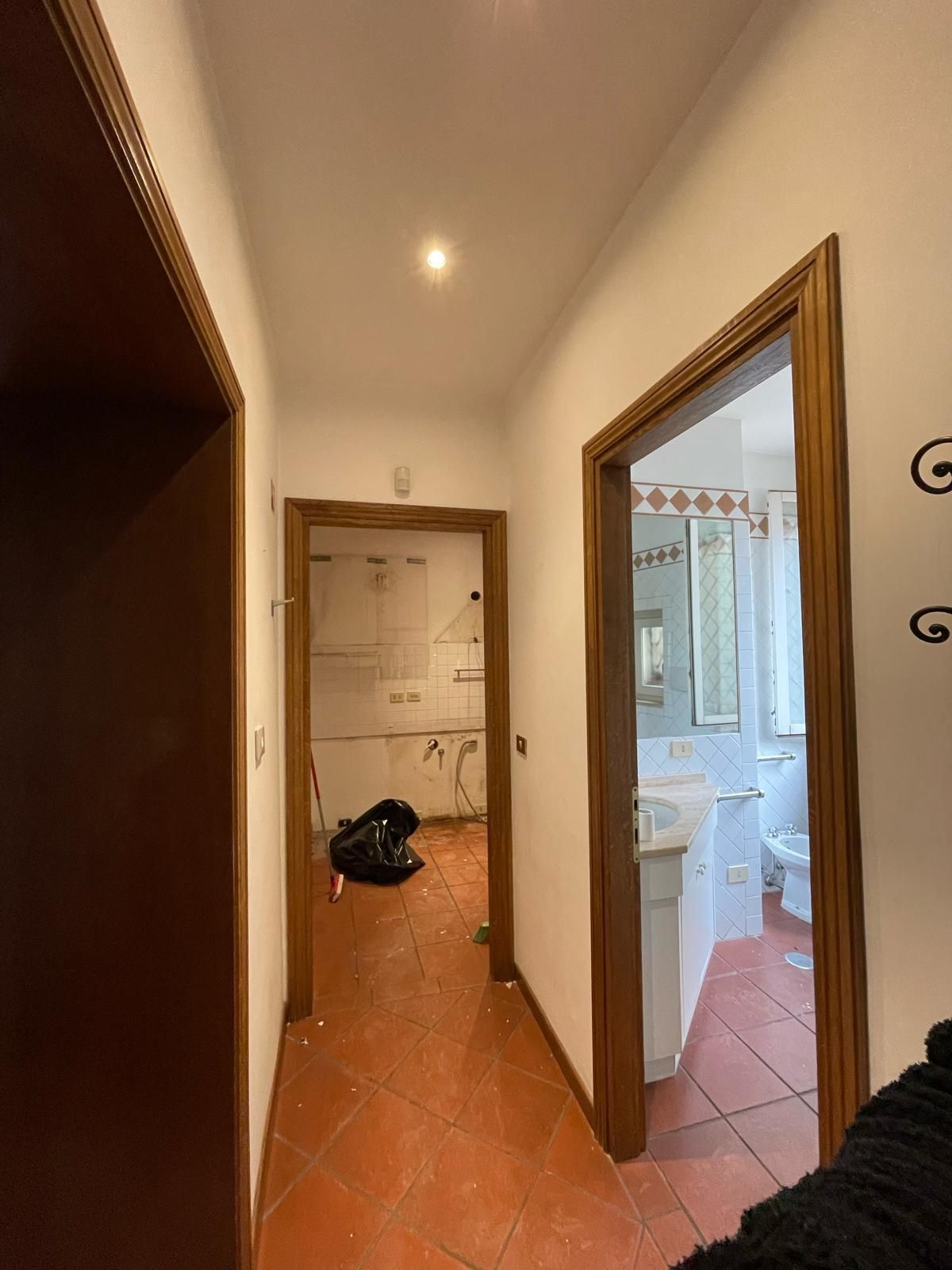 Corridoio con pavimento in cotto, porte di accesso alla cucina e al bagno.