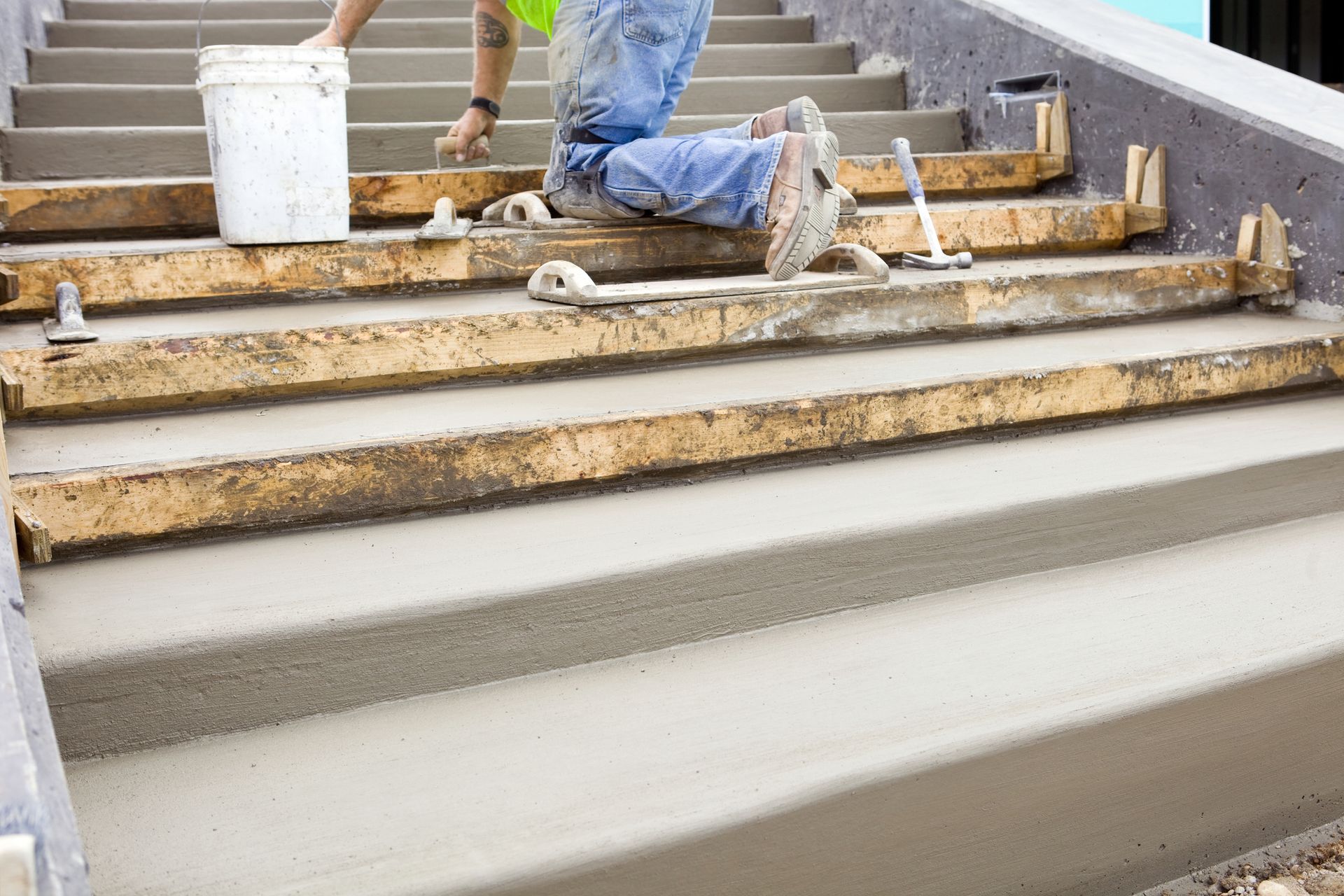 Construction worker smoothing freshly poured concrete on stairs using wooden forms and tools. Construction worker smoothing freshly poured concrete on stairs using wooden forms and tools.