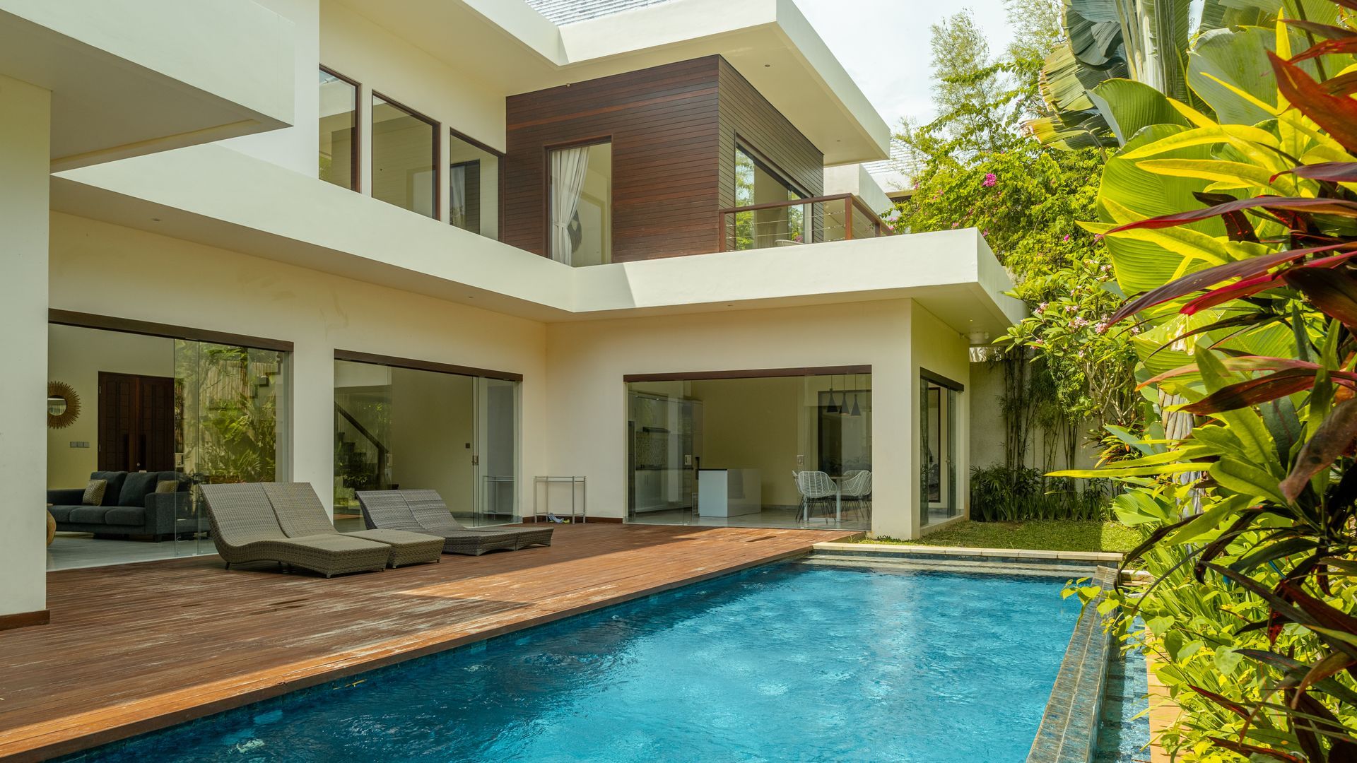 Large white house with many windows, a swimming pool, and a landscaped garden