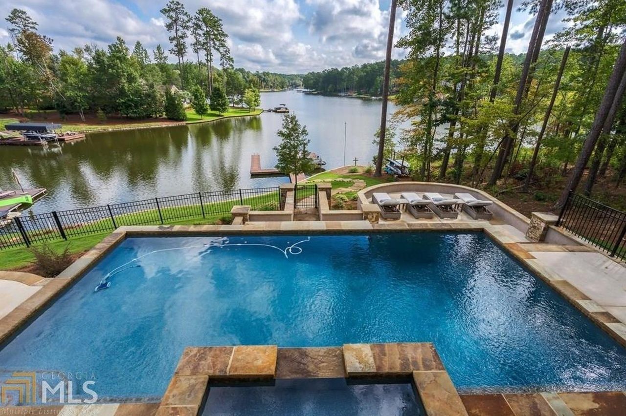 Swimming pool overlooking a lake, surrounded by trees.