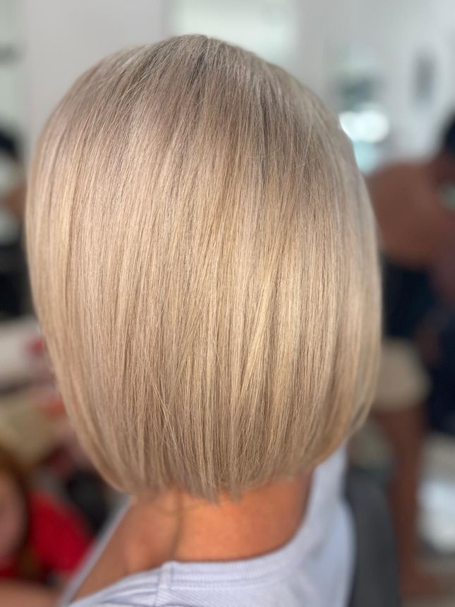 Short blonde bob haircut viewed from the back in a blurred indoor setting