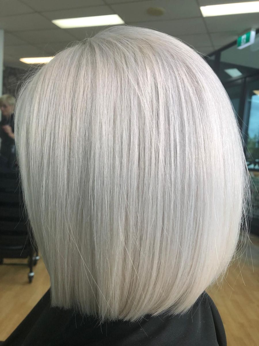 Short platinum-blonde bob haircut shown from the back in a salon chair