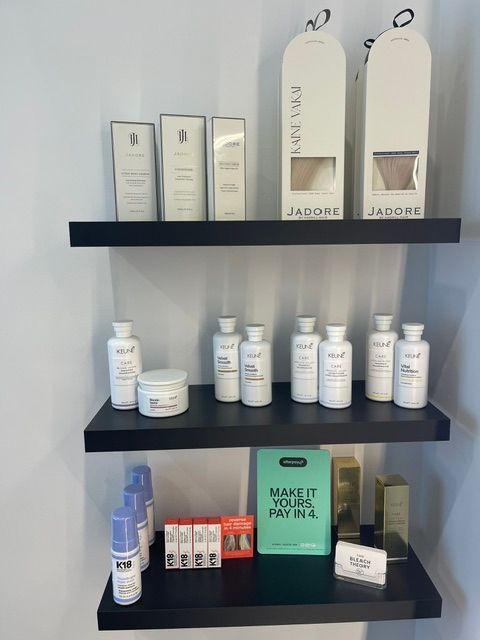Shelves displaying white and blue skincare products and bottles on a black wall rack