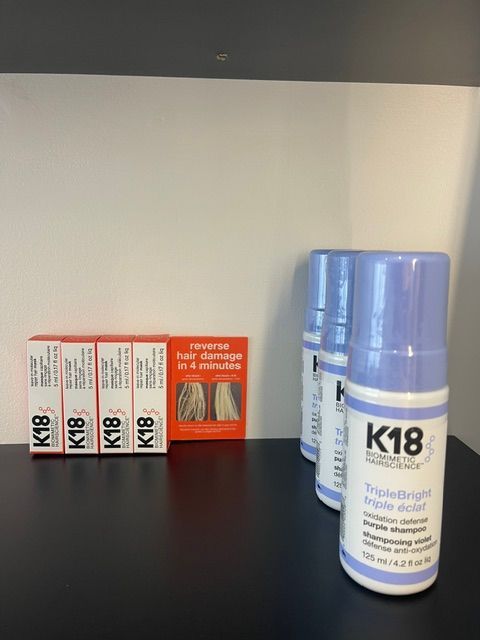 K18 hair care products on a shelf, including boxed items and blue bottles.