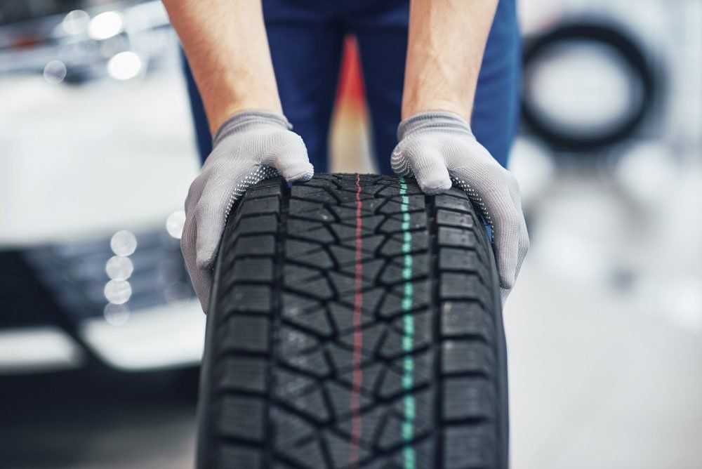 Mechanic Holding A Tyre Replacement — Evco Automotive in South Albury, NSW