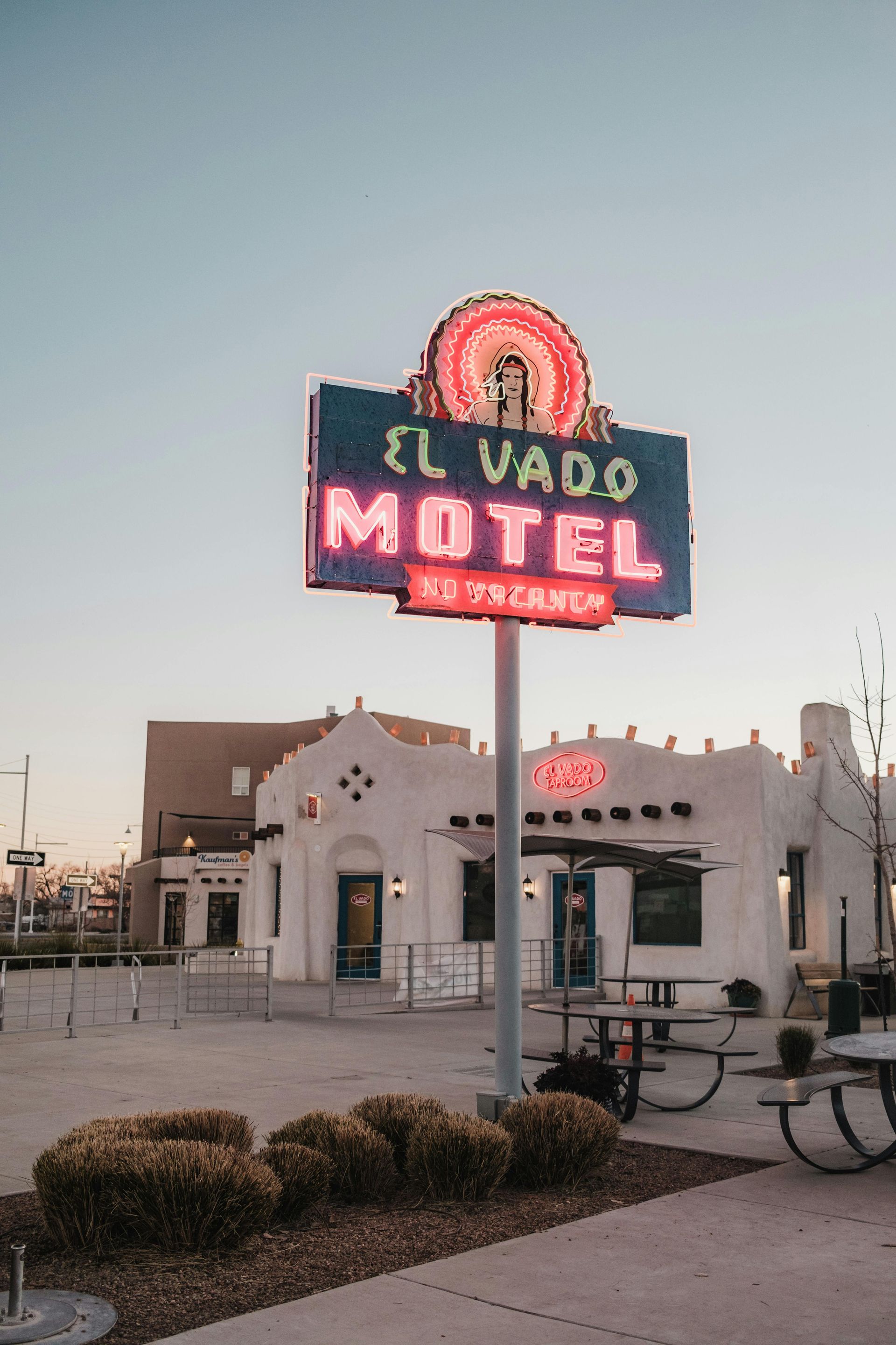 A motel sign is lit up in front of a white building.