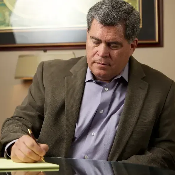 A man in a suit is writing on a piece of paper