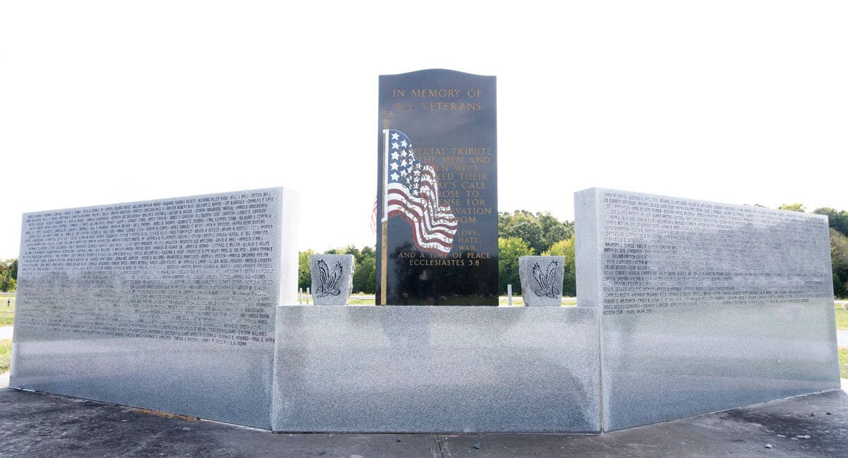 Abstract memorial of clear glass panels around a dark central monument with an American flag design.