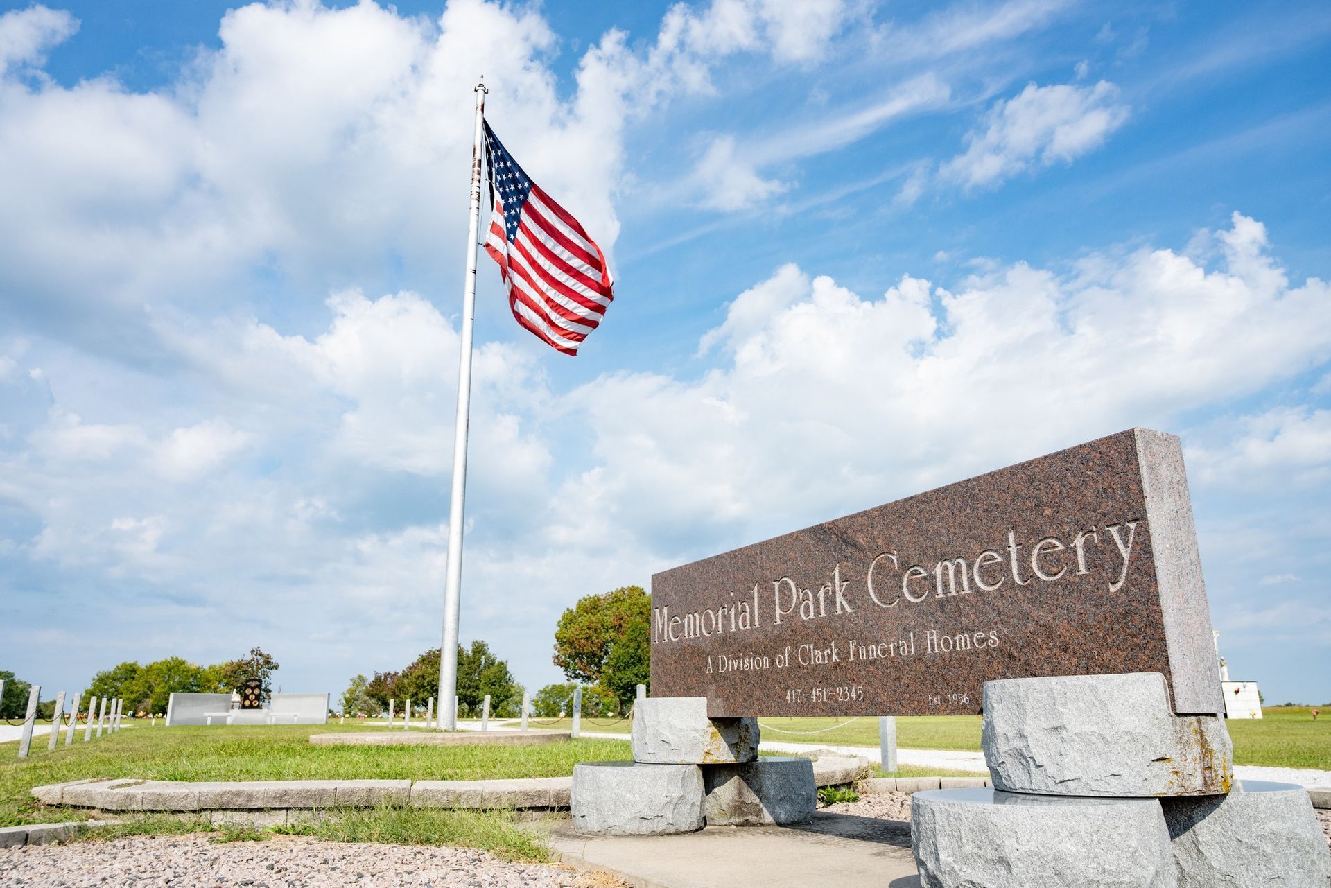 Calvary Park Cemetery entrance sign with a U.S. flag on a flagpole under a blue sky