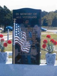 Veterans memorial monument with American flags and red flowers outdoors