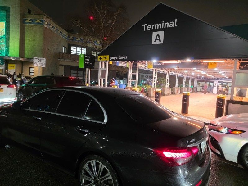 Cars in front of Terminal A entrance at night. Signage lit up.
