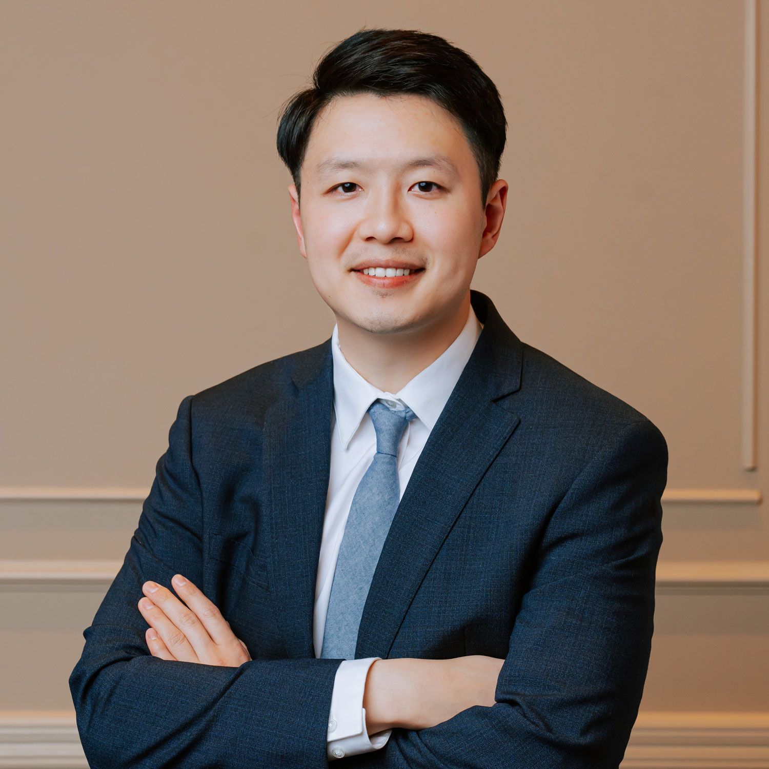 A man in a suit and tie is standing with his arms crossed.