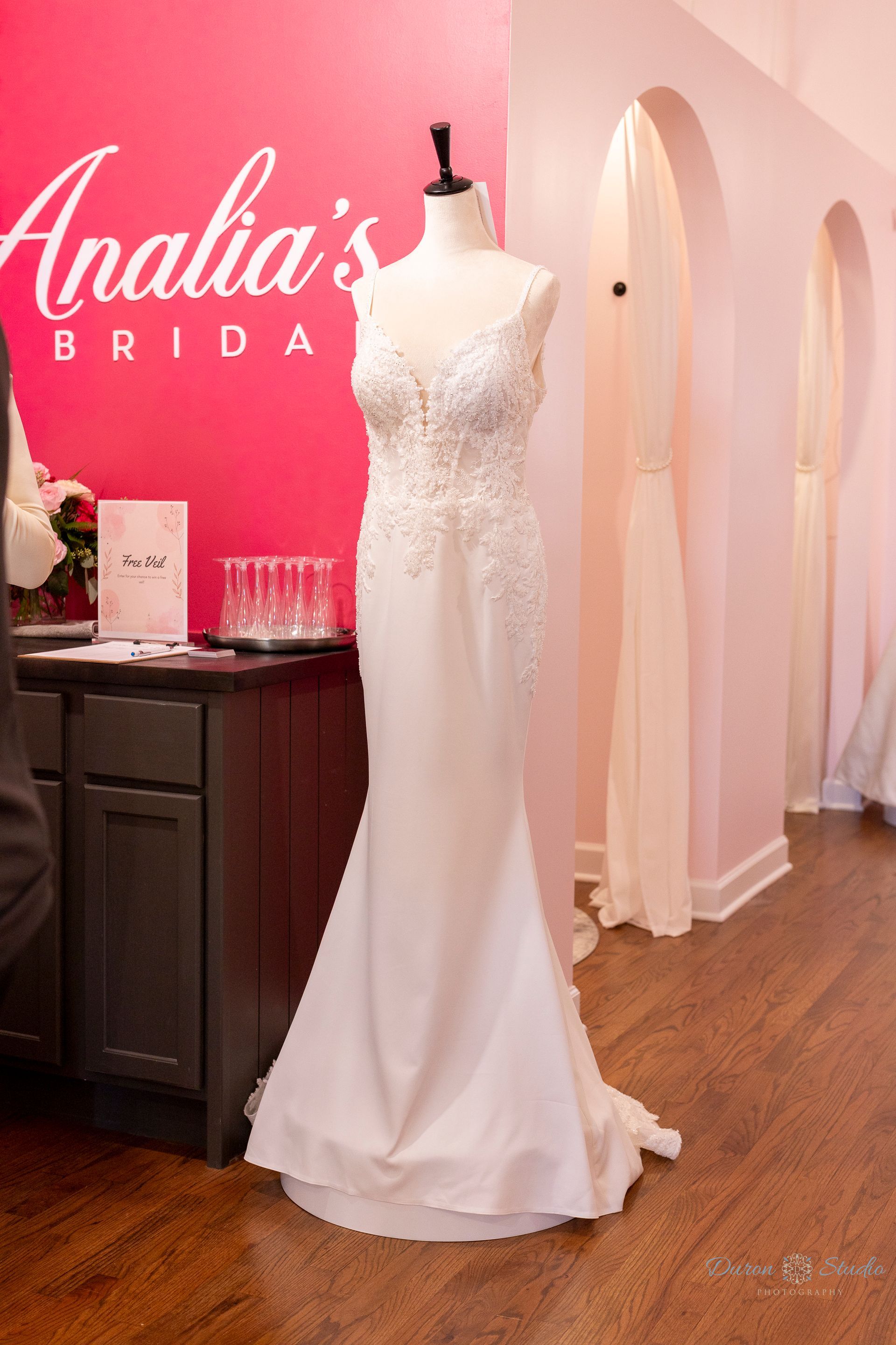 White lace bridal gown on a mannequin inside a pink wedding dress boutique