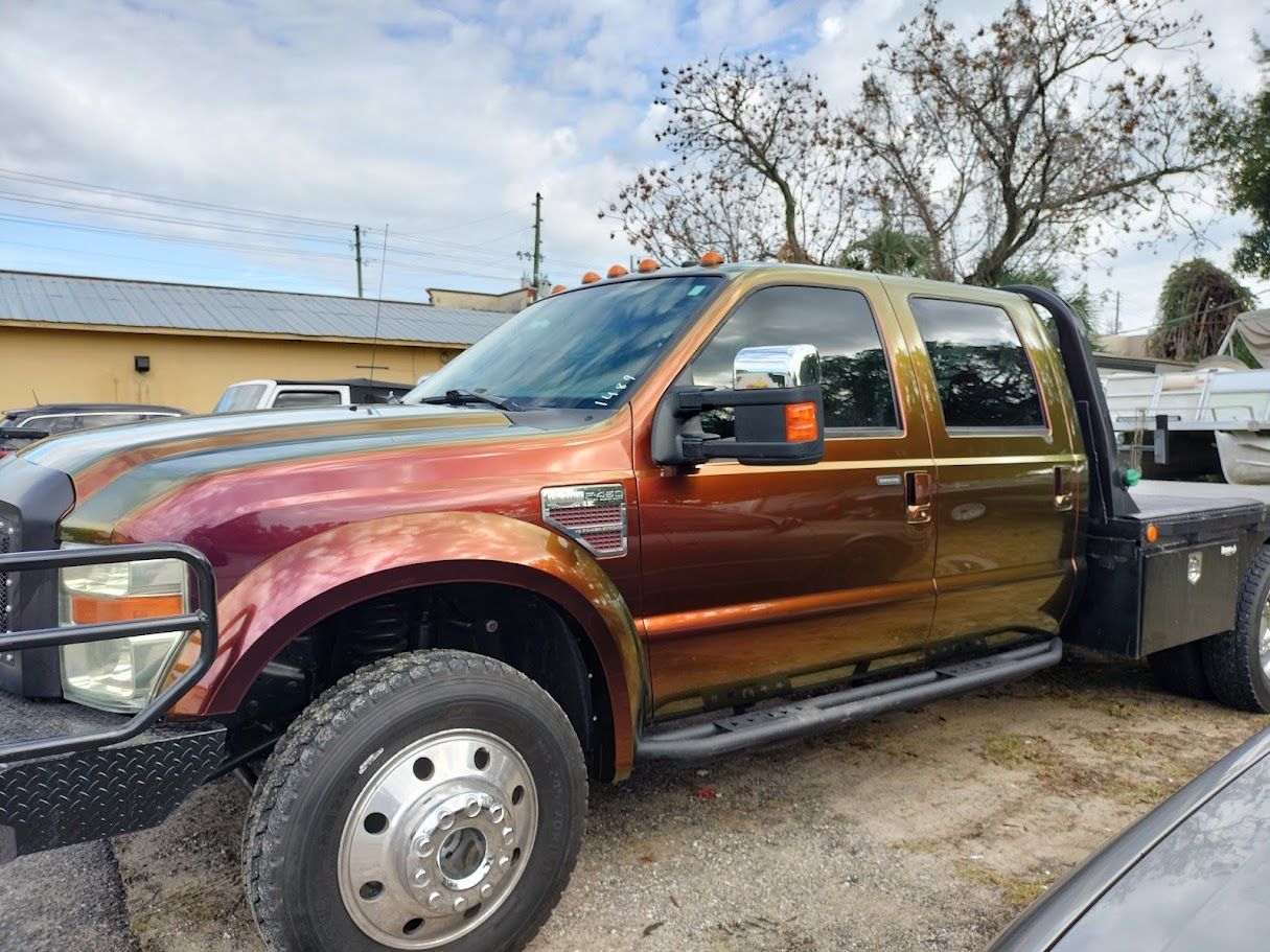 Ford F-450 flatbed truck with a custom, color-shifting paint job, parked outdoors on a sunny day.
