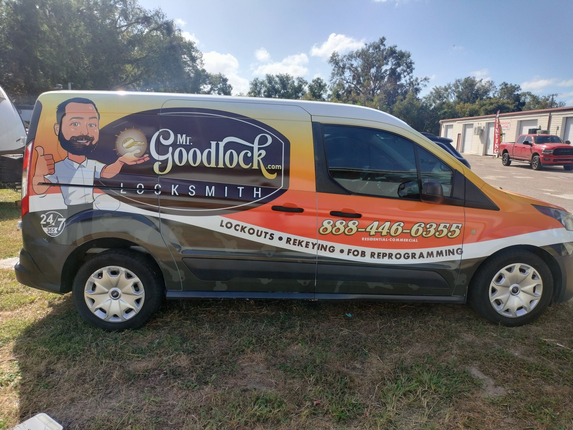 Mr. Goodlock Locksmith van with logo and phone number, parked outdoors. Orange and gold color scheme.