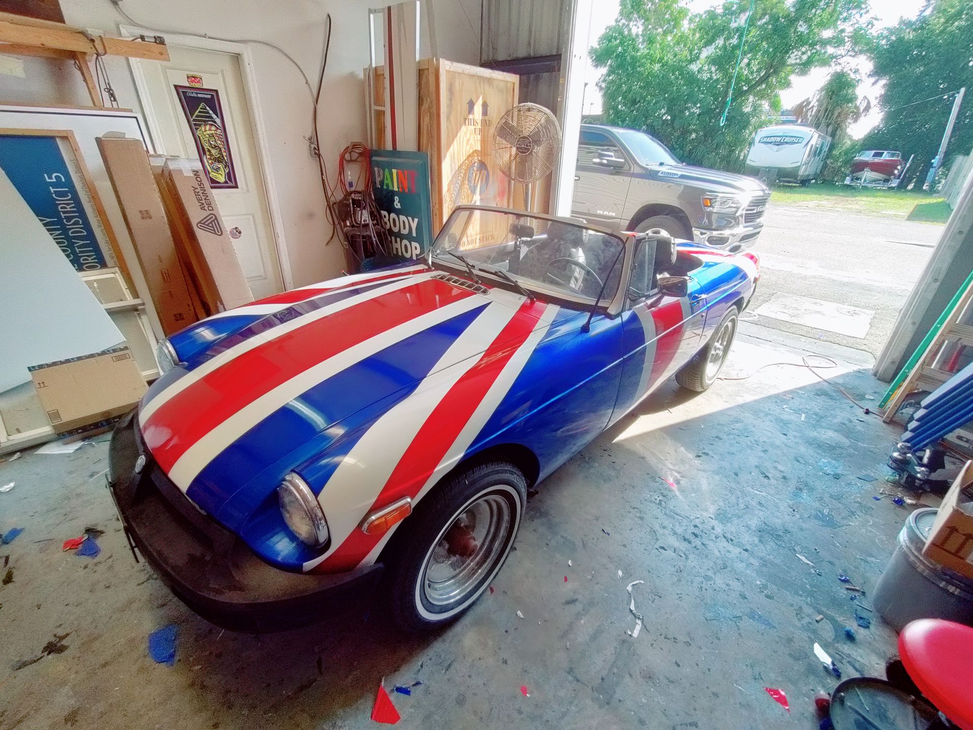 British flag-painted convertible car parked in a garage with other items.