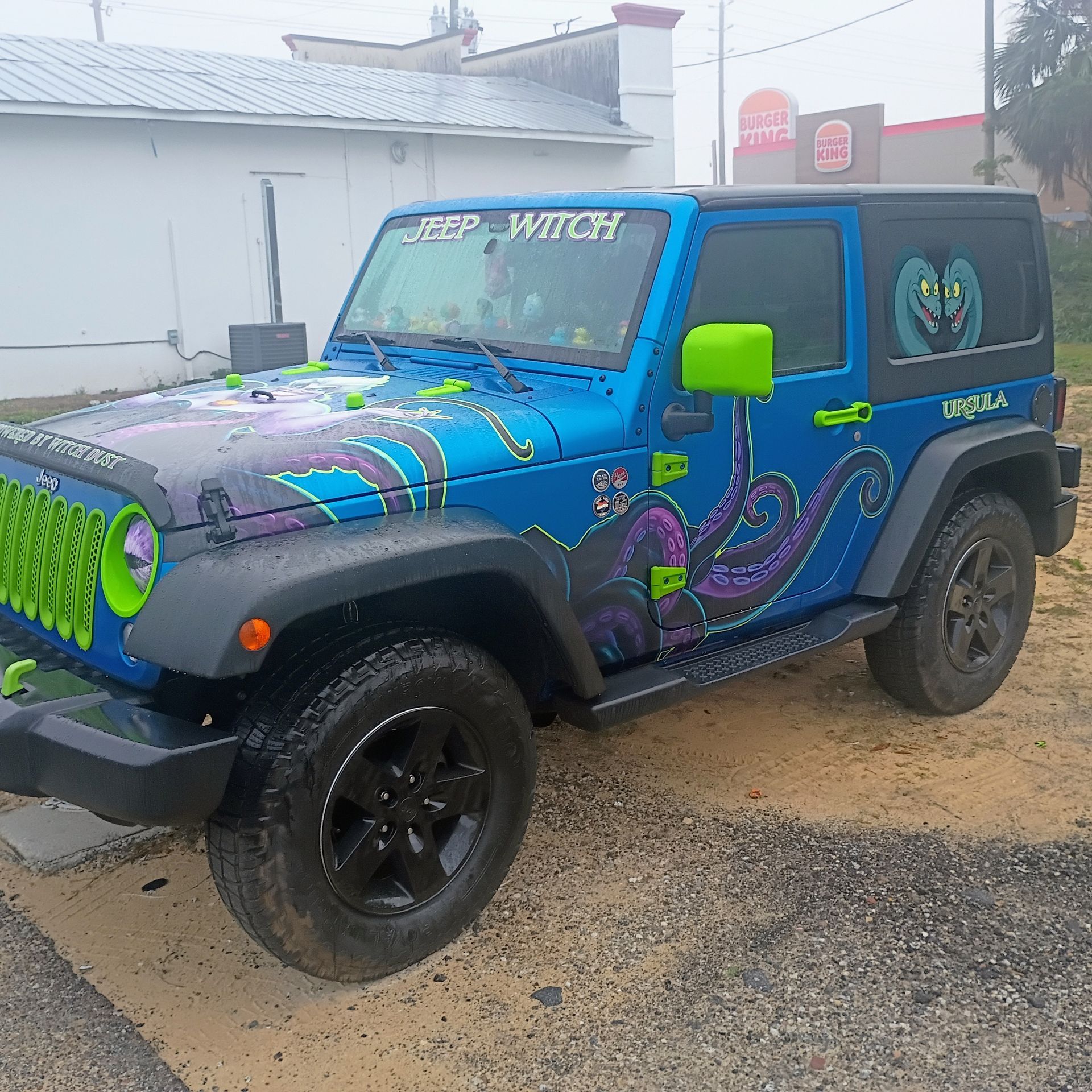 Blue Jeep Wrangler with tentacle design and green accents parked outside.