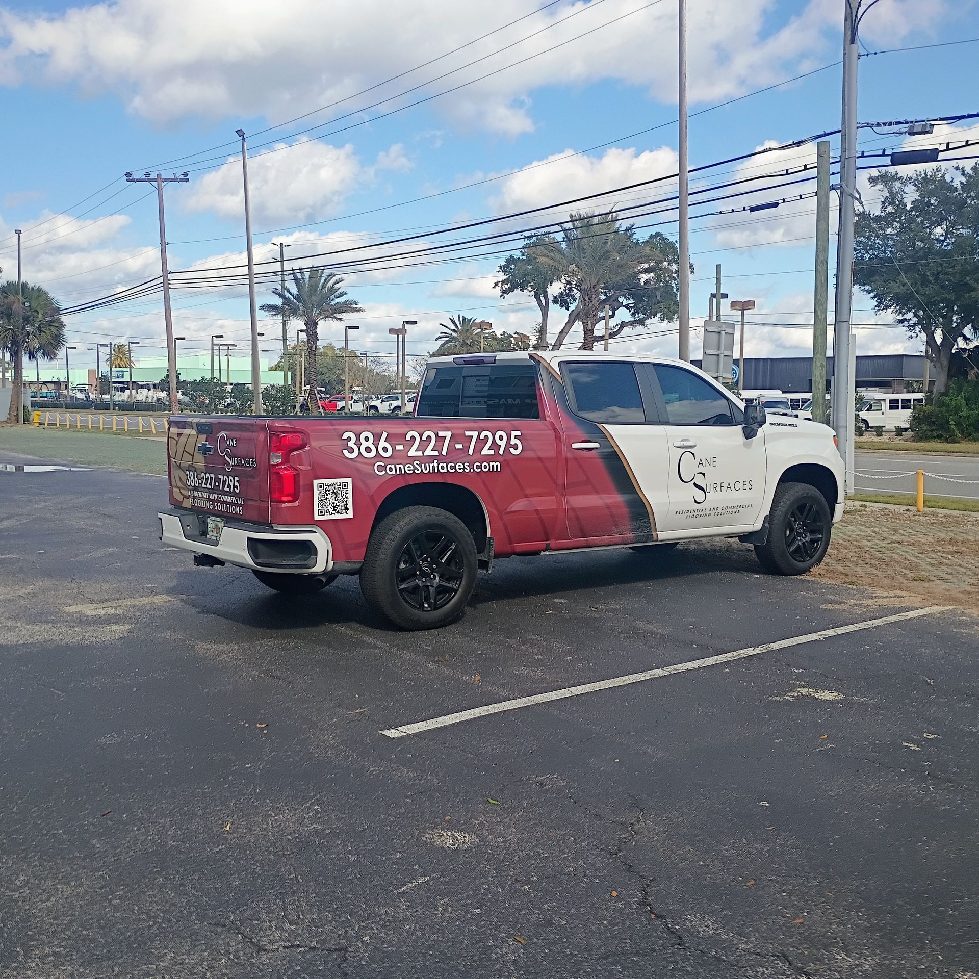 Red and white truck with business advertisement parked in a lot. Phone number and logo are visible.