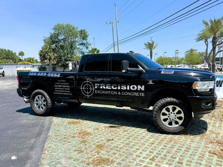 Black Precision Excavation & Concrete truck parked outdoors on a sunny day.