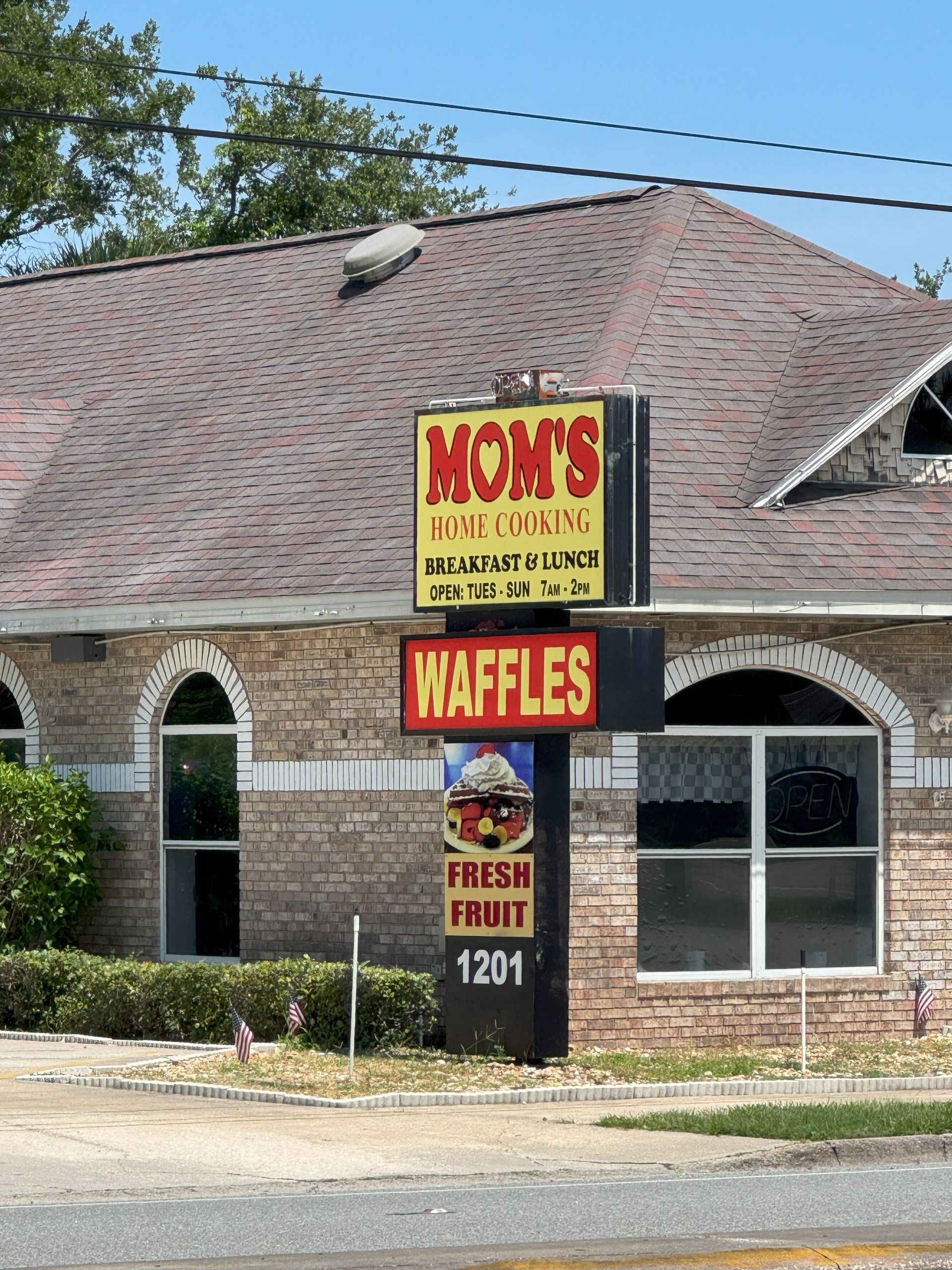 Sign for Mom's Place offering waffles, in front of a brick building at 1201.