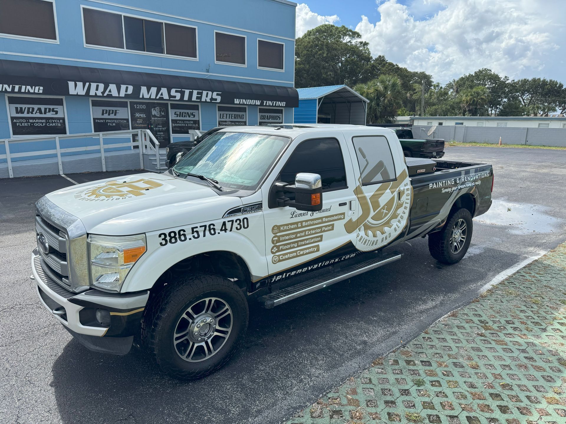 White pickup truck with business wrap parked outside Wrap Masters building.