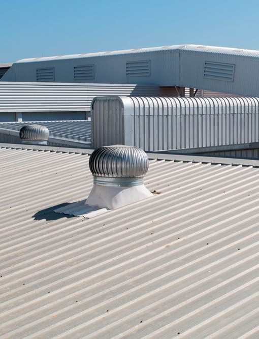 Rooftop with corrugated metal vents and HVAC units under a clear sky.