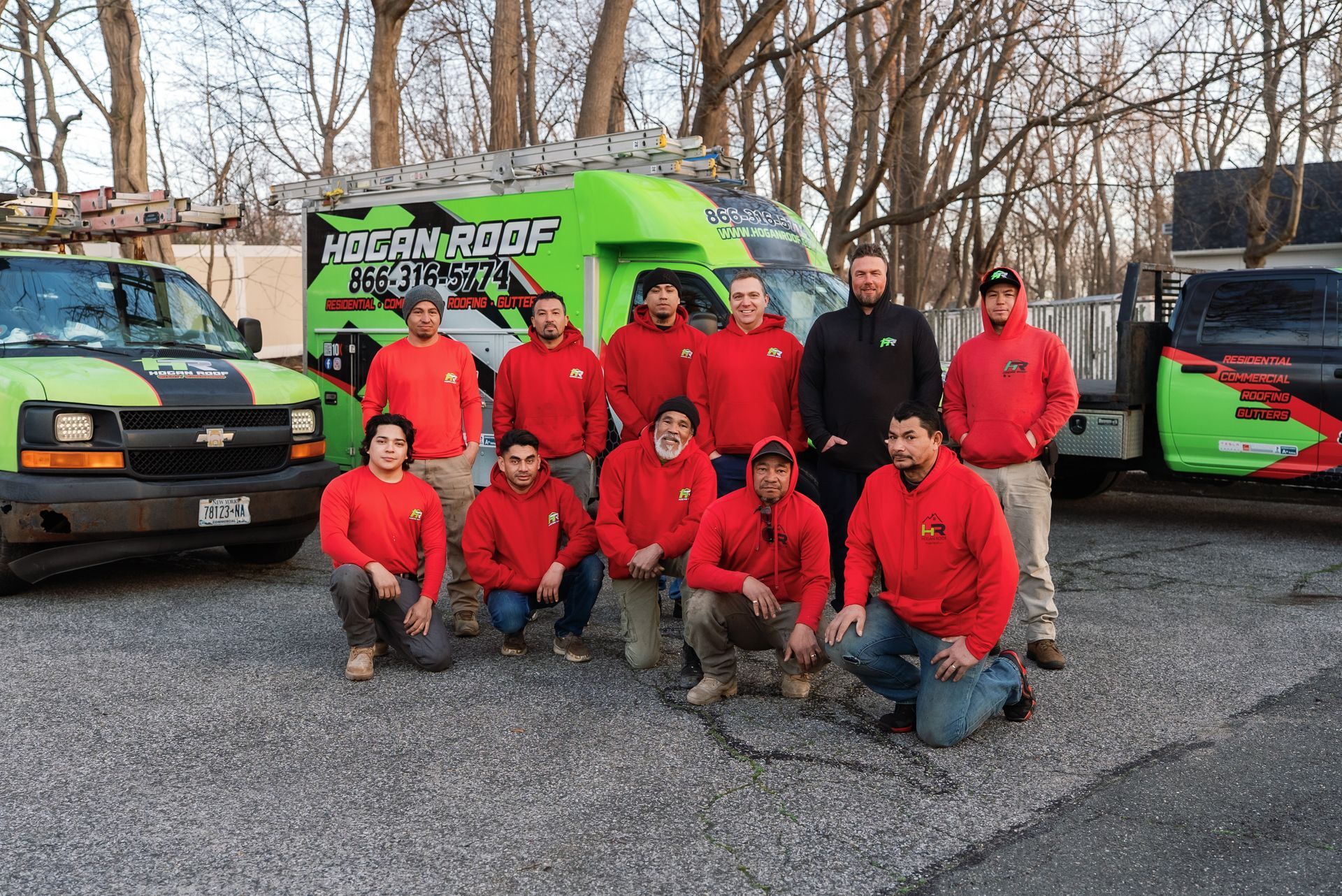 Group in red jackets posing with bright green service trucks in a parking lot