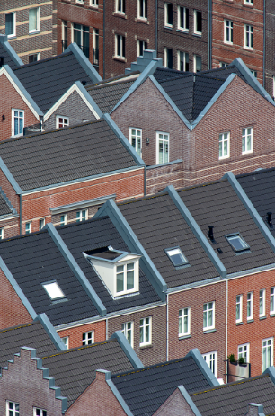 Aerial view of red brick row houses with dark gray roofs and skylights.