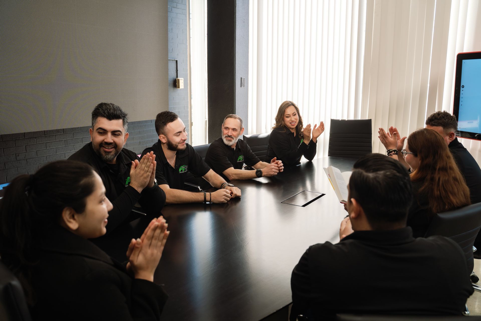People seated around a conference table in a meeting room, with one person speaking at the head.