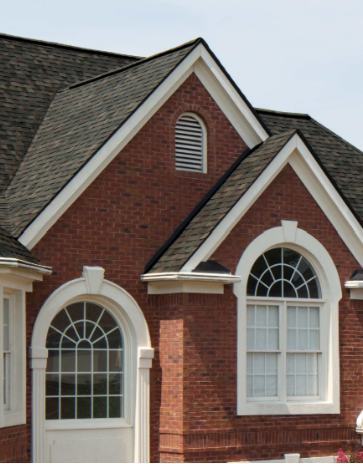 Brick house exterior with white trim, arched windows, and a dark shingled roof.
