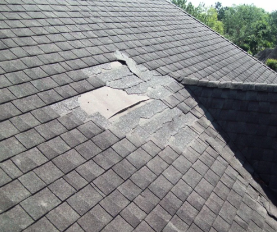 Damaged shingle roof with a patched section near a valley