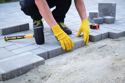 The master in yellow gloves lays paving stones in layers.