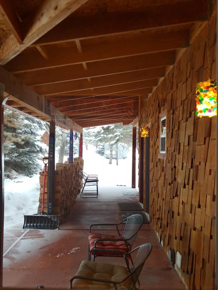 A covered porch with chairs and a bench in the snow