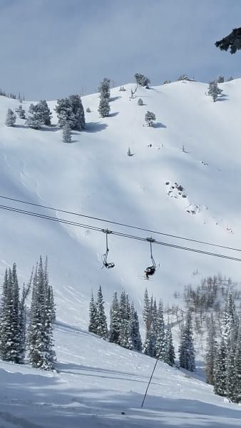 A ski lift going up a snow covered mountain