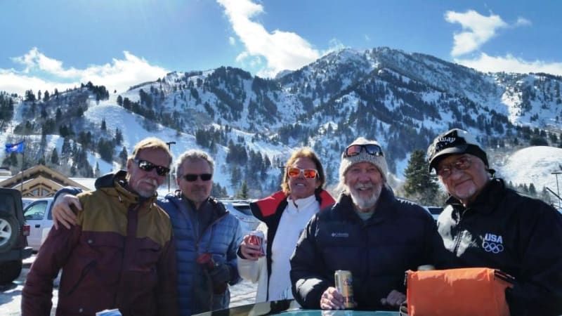 A group of men are posing for a picture in front of a snowy mountain.
