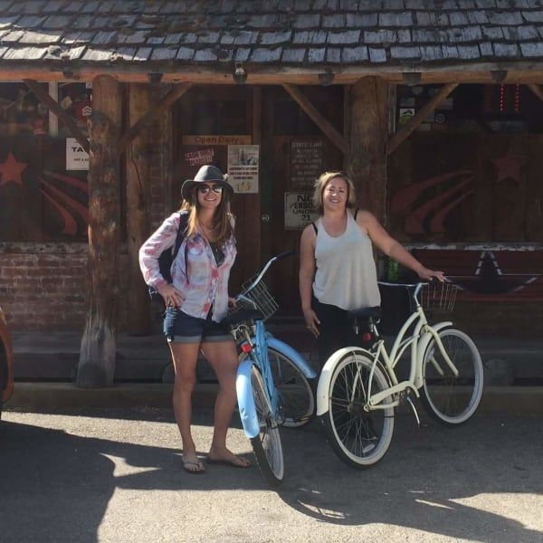 Two women standing next to bicycles in front of a building