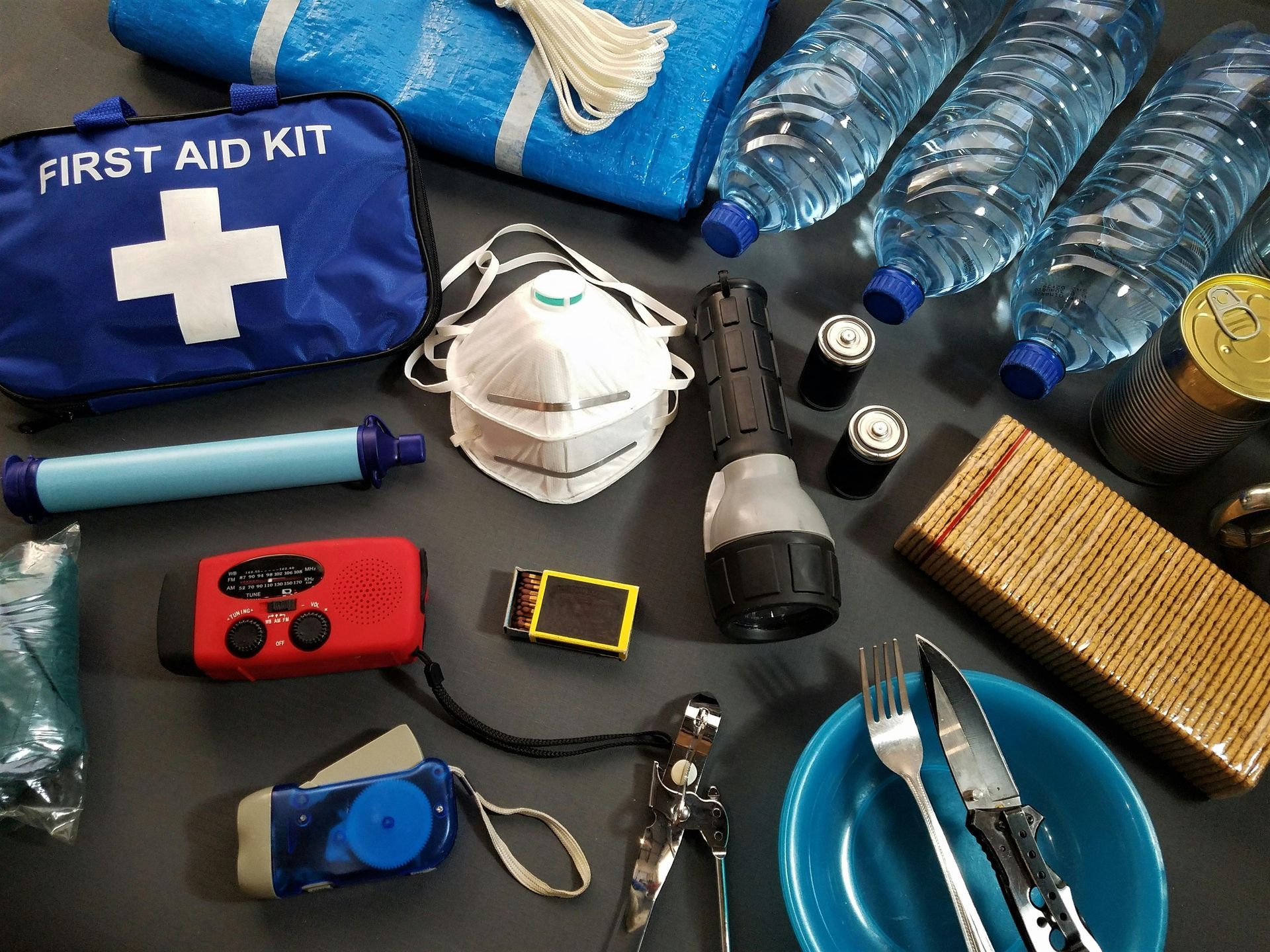 Emergency preparedness kit with first aid, water, food, radio, flashlight, and mask.